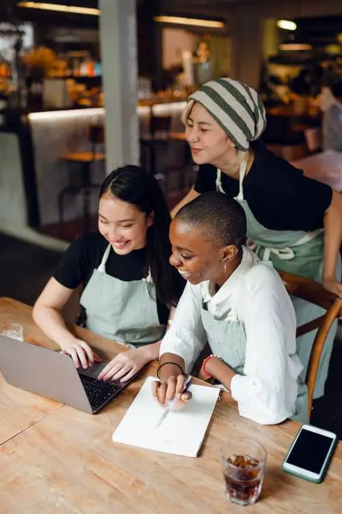 3 people smiling and looking at a laptop